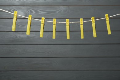 Colorful plastic clothespins on rope against wooden background. Space for text