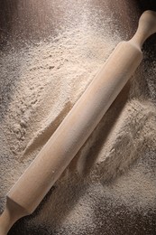 Pile of flour and rolling pin on wooden table, top view