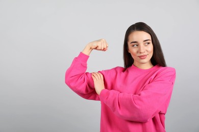 Strong woman as symbol of girl power on light grey background. 8 March concept