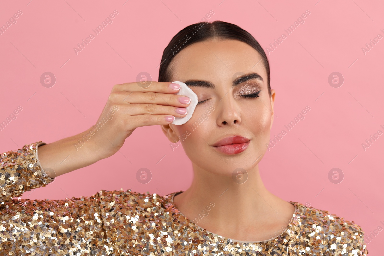 Photo of Beautiful woman removing makeup with cotton pad on pink background