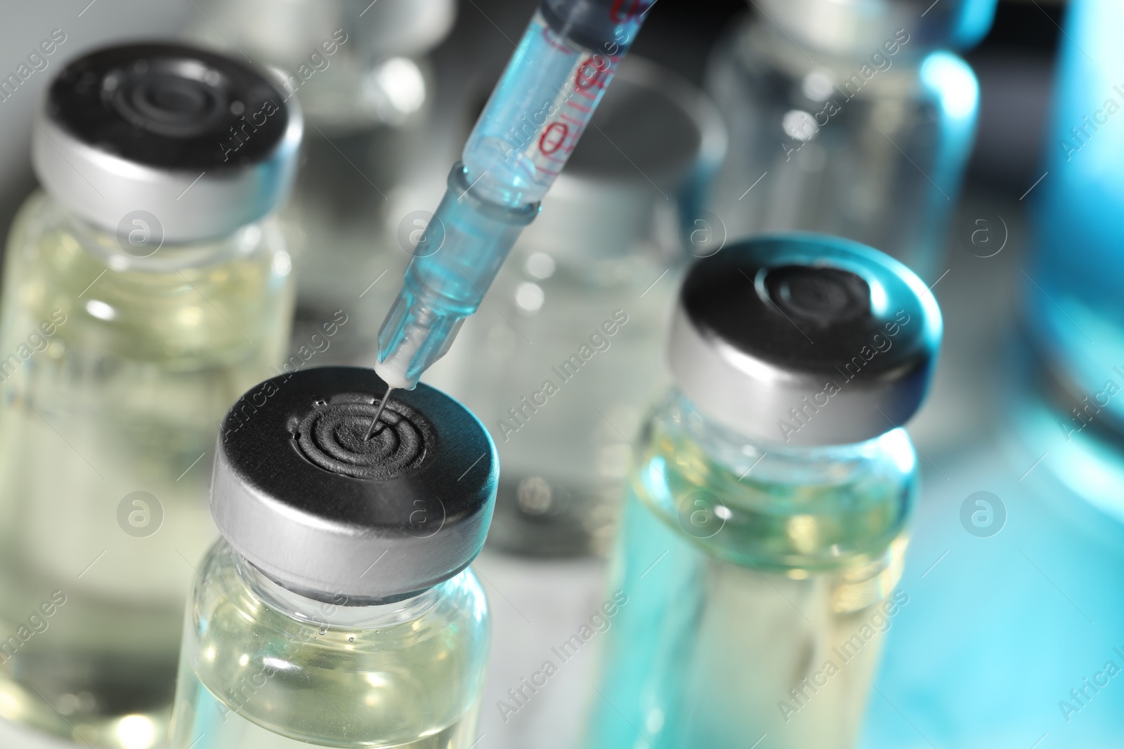 Photo of Filling syringe with medicine from vial on table, closeup