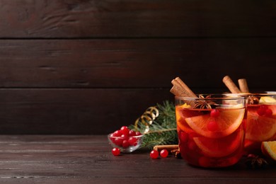 Photo of Delicious punch drink with cranberries and orange on wooden table. Space for text