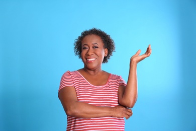 Portrait of happy African-American woman on light blue background