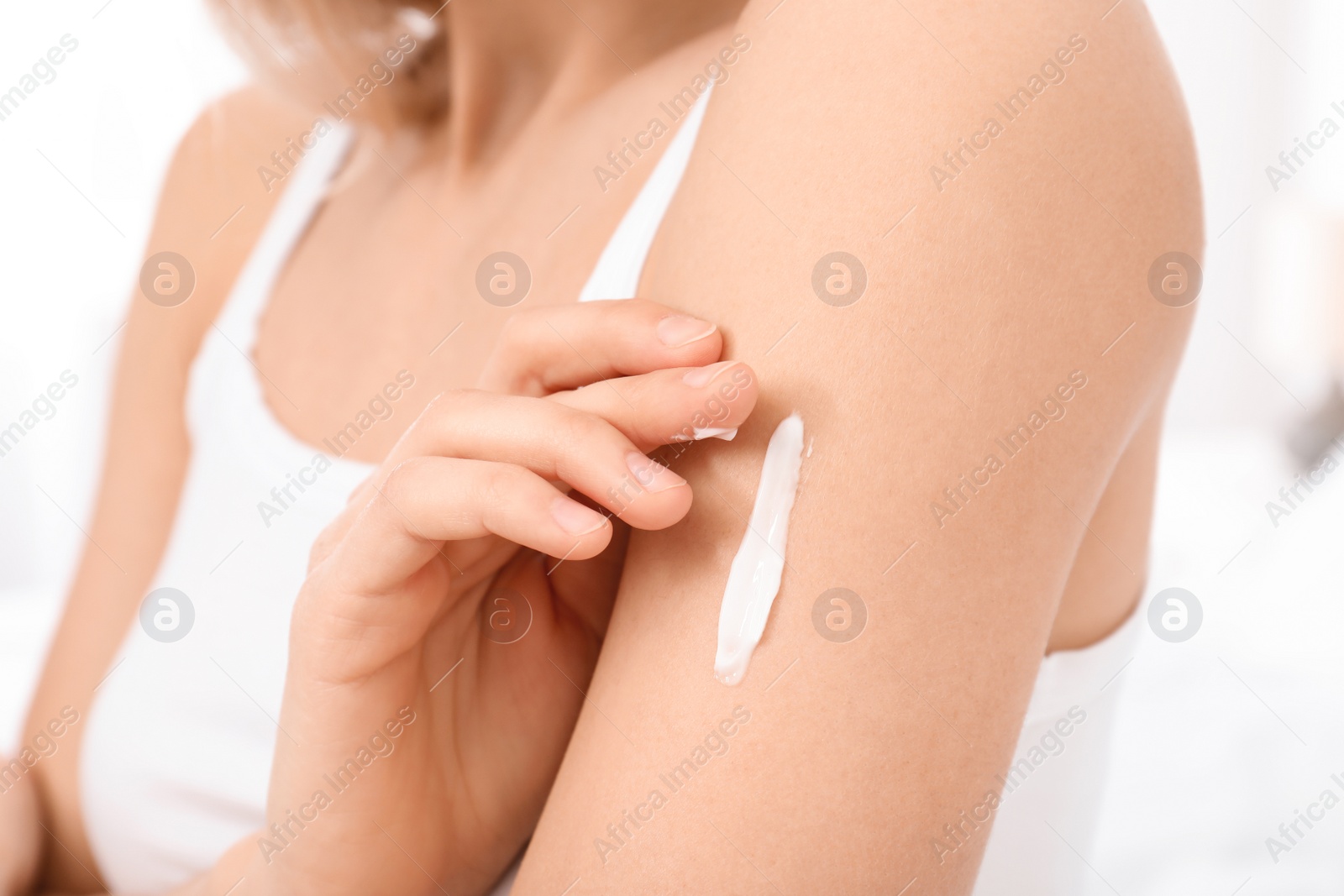 Photo of Young woman applying cream, closeup. Beauty and body care