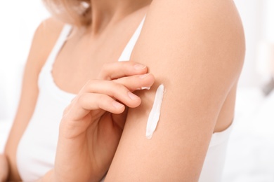 Young woman applying cream, closeup. Beauty and body care