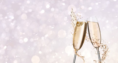 Image of Glasses with sparkling wine and splashes on light background, space for text. Banner design