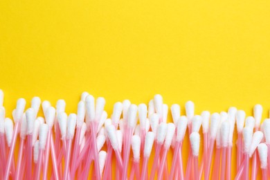 Photo of Many cotton buds on yellow background, flat lay. Space for text