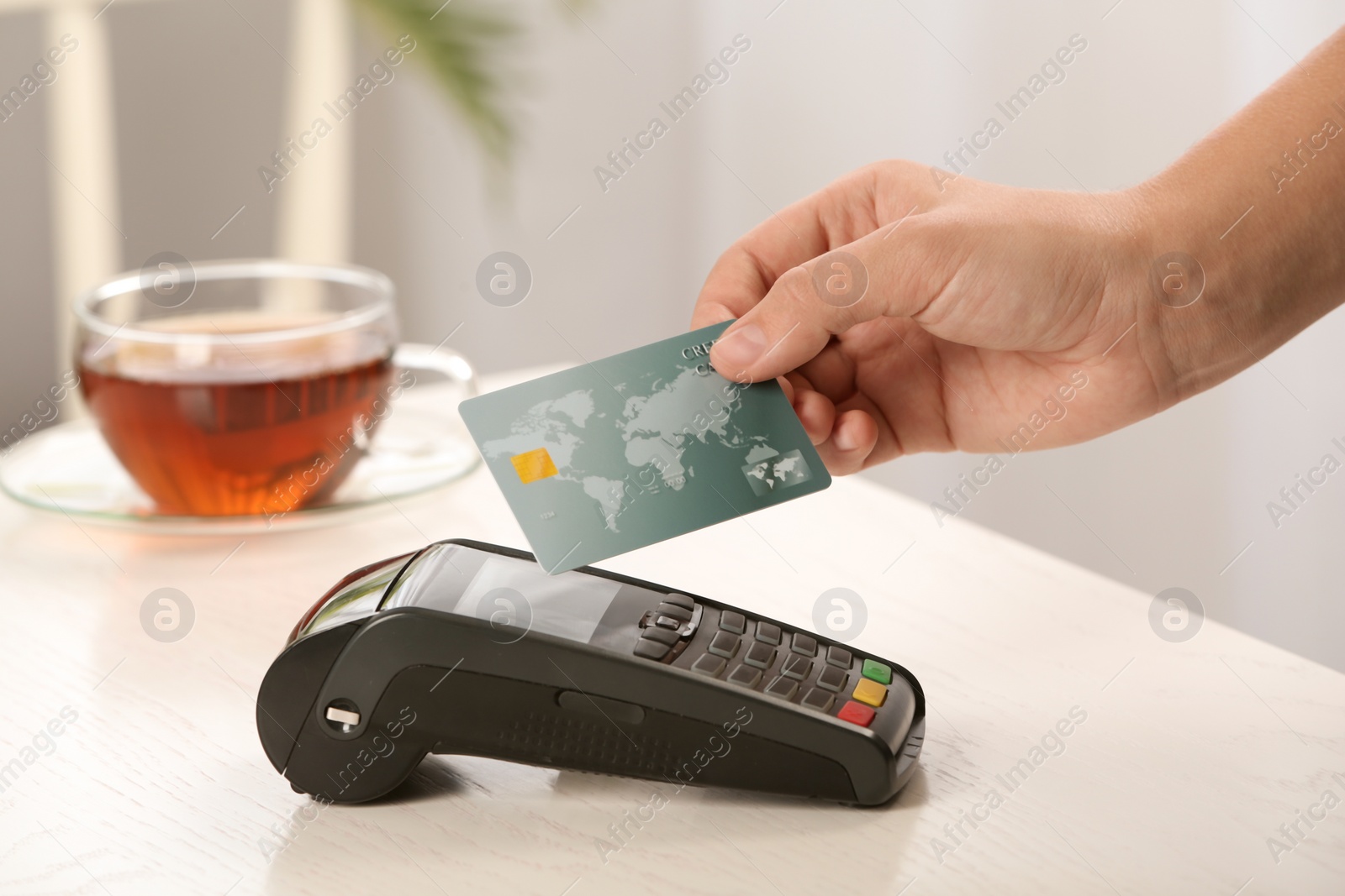 Photo of Woman using terminal for contactless payment with credit card in cafe