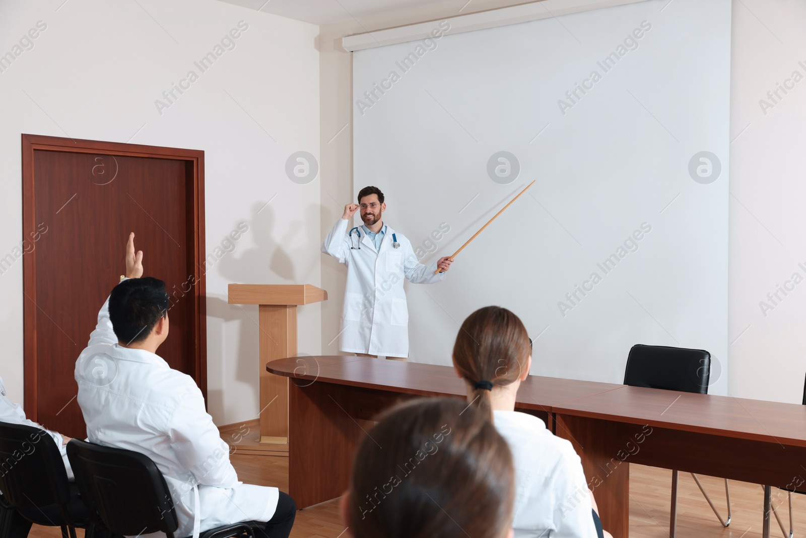 Photo of Doctor giving lecture in conference room with projection screen