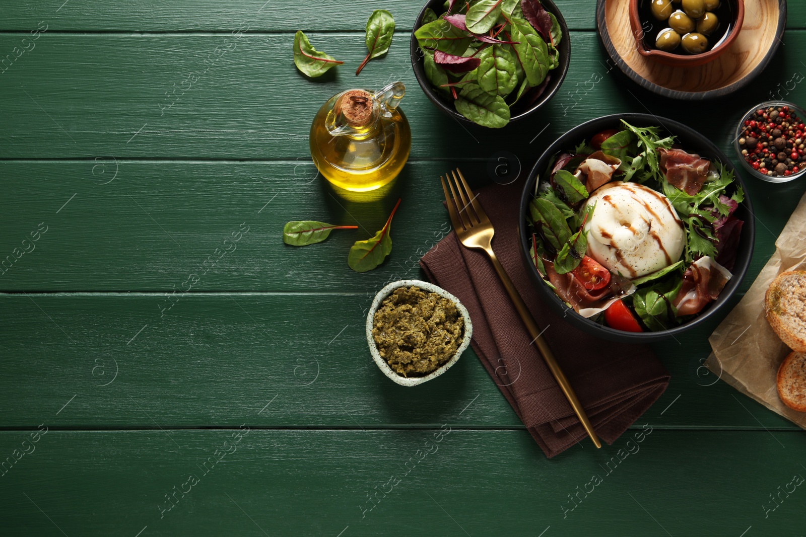 Photo of Delicious burrata salad served on green wooden table, flat lay. Space for text