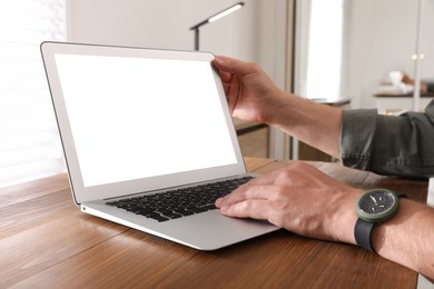 Photo of Man with modern laptop at wooden table indoors, closeup. Space for design