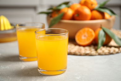 Photo of Glasses of fresh tangerine juice on marble table