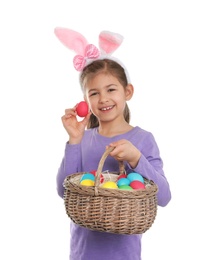 Photo of Little girl in bunny ears headband holding basket with Easter eggs on white background