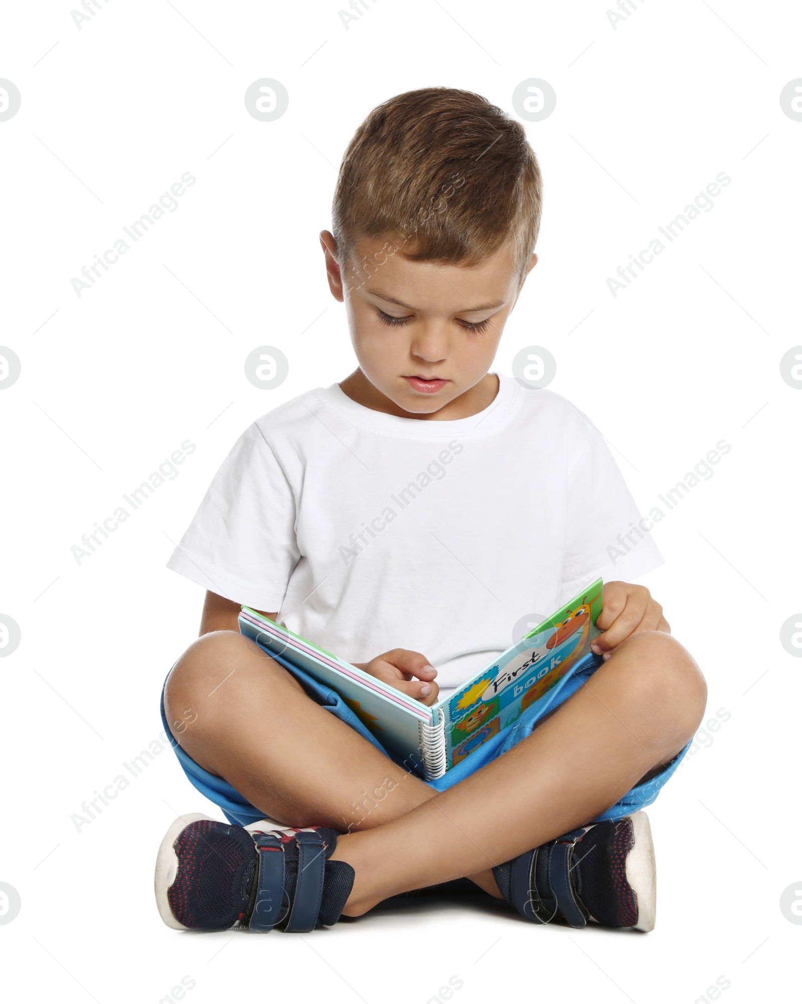 Photo of Cute little boy reading book on white background