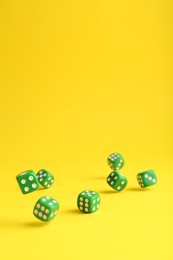Photo of Many green game dices on yellow background. Space for text