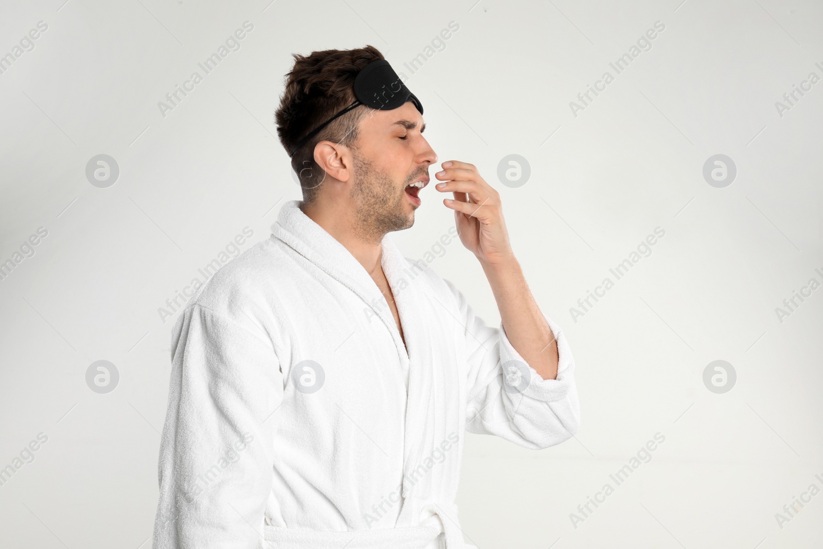 Photo of Sleepy young man in bathrobe isolated on white