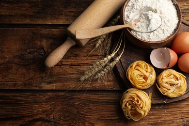 Photo of Flat lay composition with uncooked homemade pasta and ingredients on wooden table. Space for text