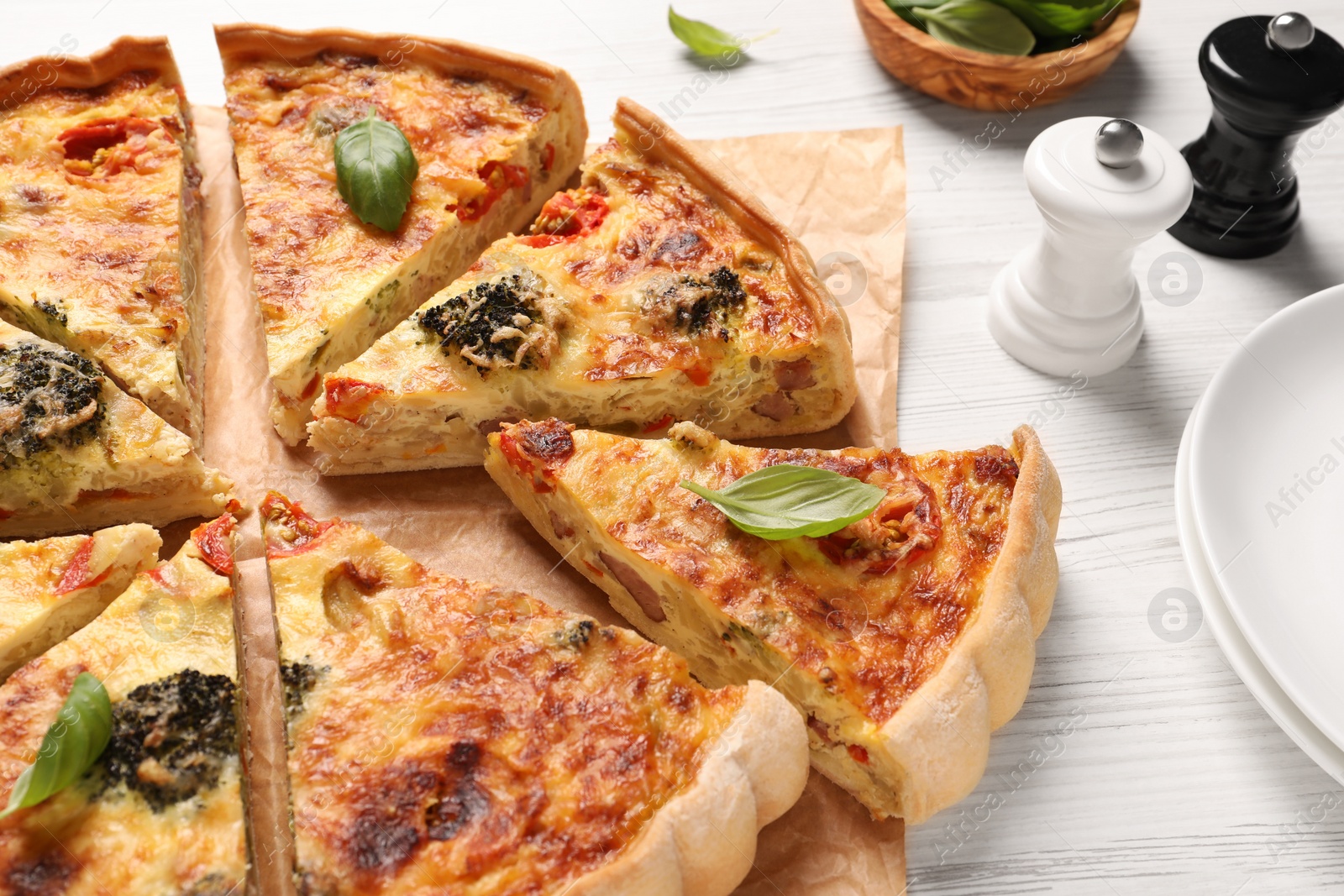 Photo of Delicious homemade vegetable quiche and spices on white table, closeup