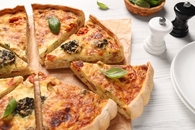 Delicious homemade vegetable quiche and spices on white table, closeup