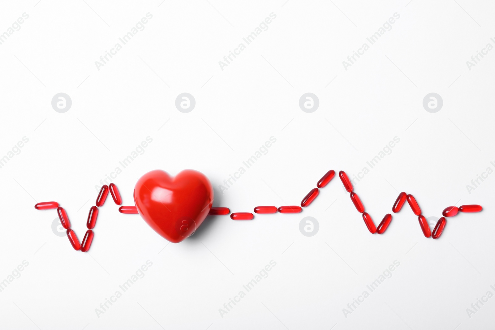 Photo of Red heart model and pills on white background. Cardiology service