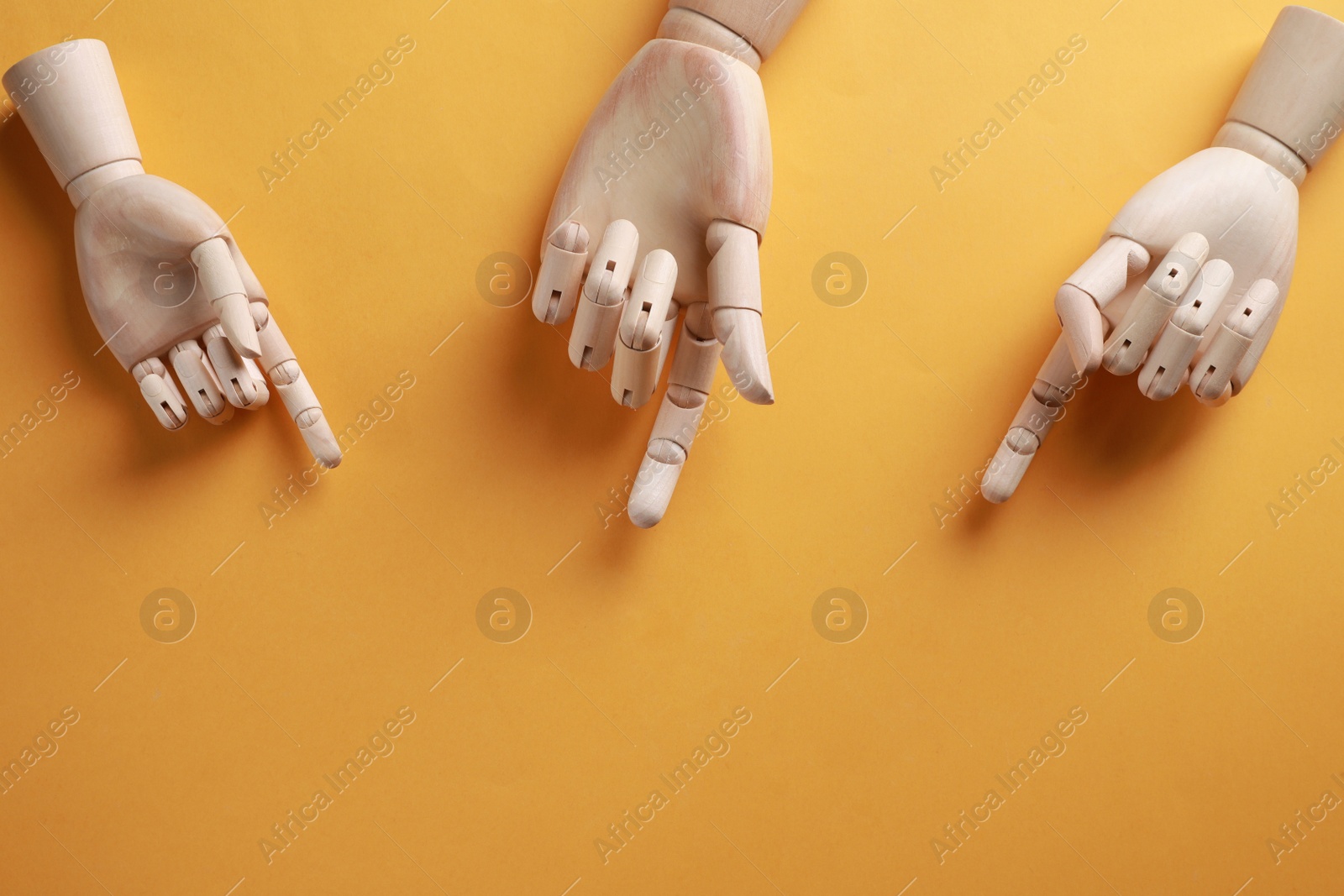 Photo of Wooden mannequin hands on orange background, flat lay. Space for text