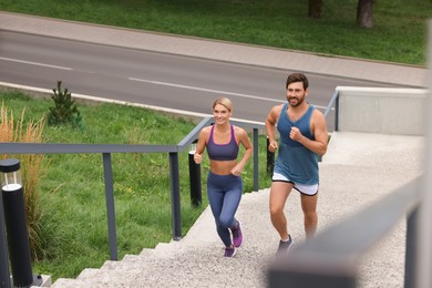 Photo of Healthy lifestyle. Happy couple running up stairs outdoors, above view