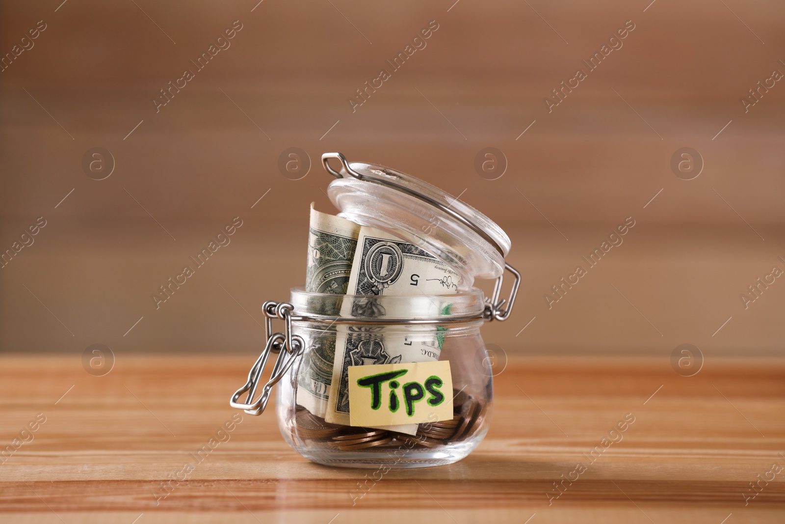 Photo of Glass jar with tips on wooden table, closeup