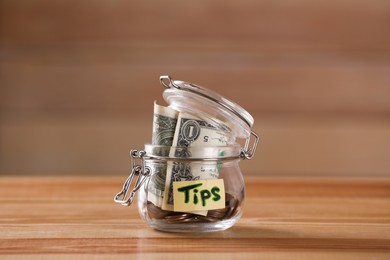 Glass jar with tips on wooden table, closeup