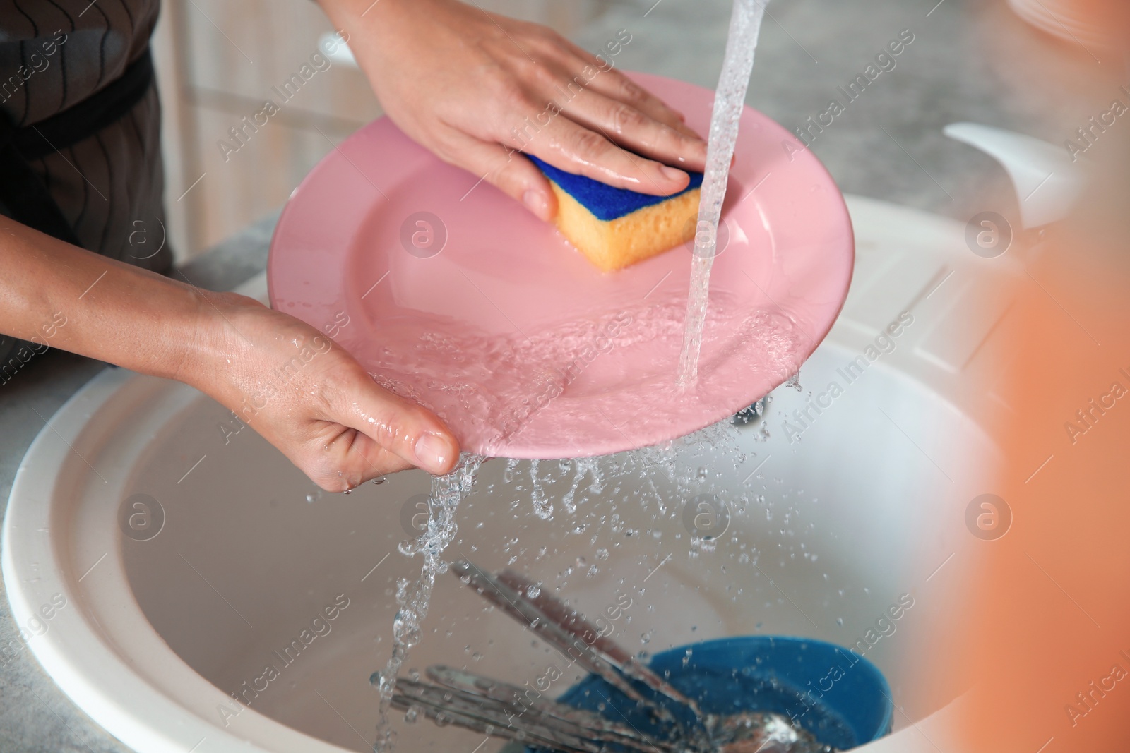 Photo of Woman washing dishes in kitchen sink, closeup view. Cleaning chores