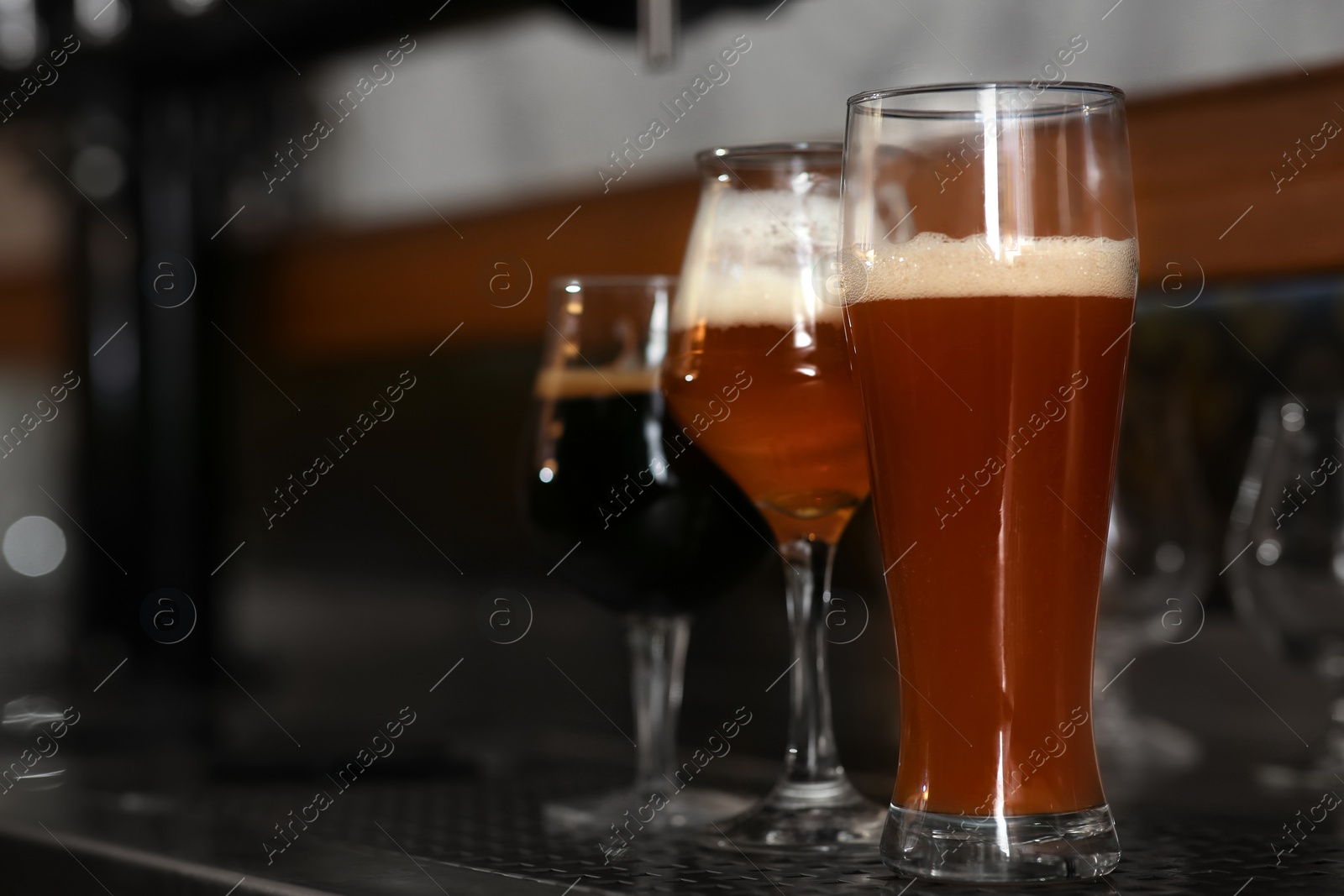 Photo of Different beers in glasses on bar counter, space for text