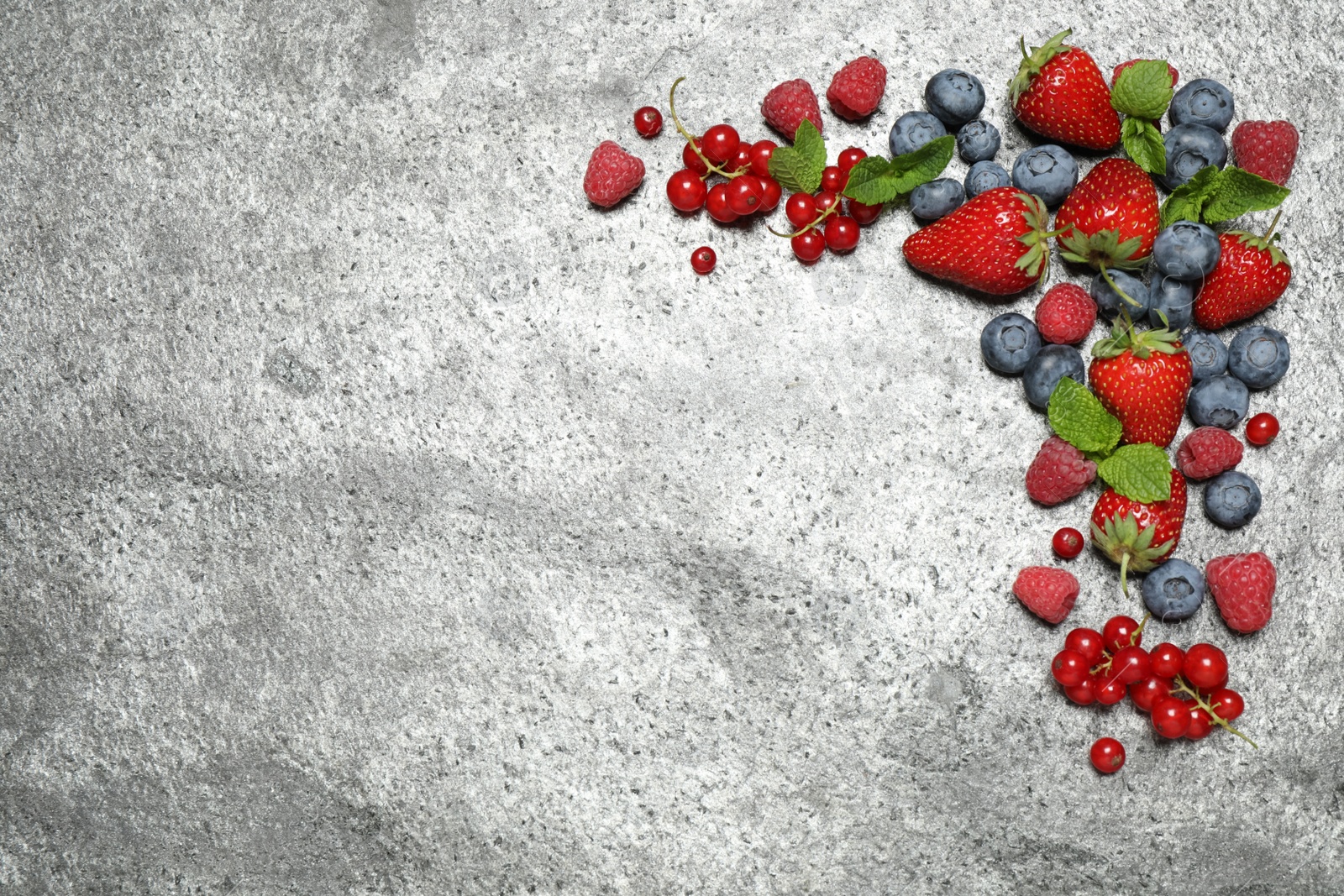 Photo of Different fresh berries on grey background, flat lay. Space for text