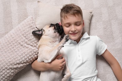 Photo of Boy with his cute pug lying on floor at home, top view