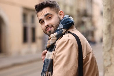 Photo of Smiling man in warm scarf on city street