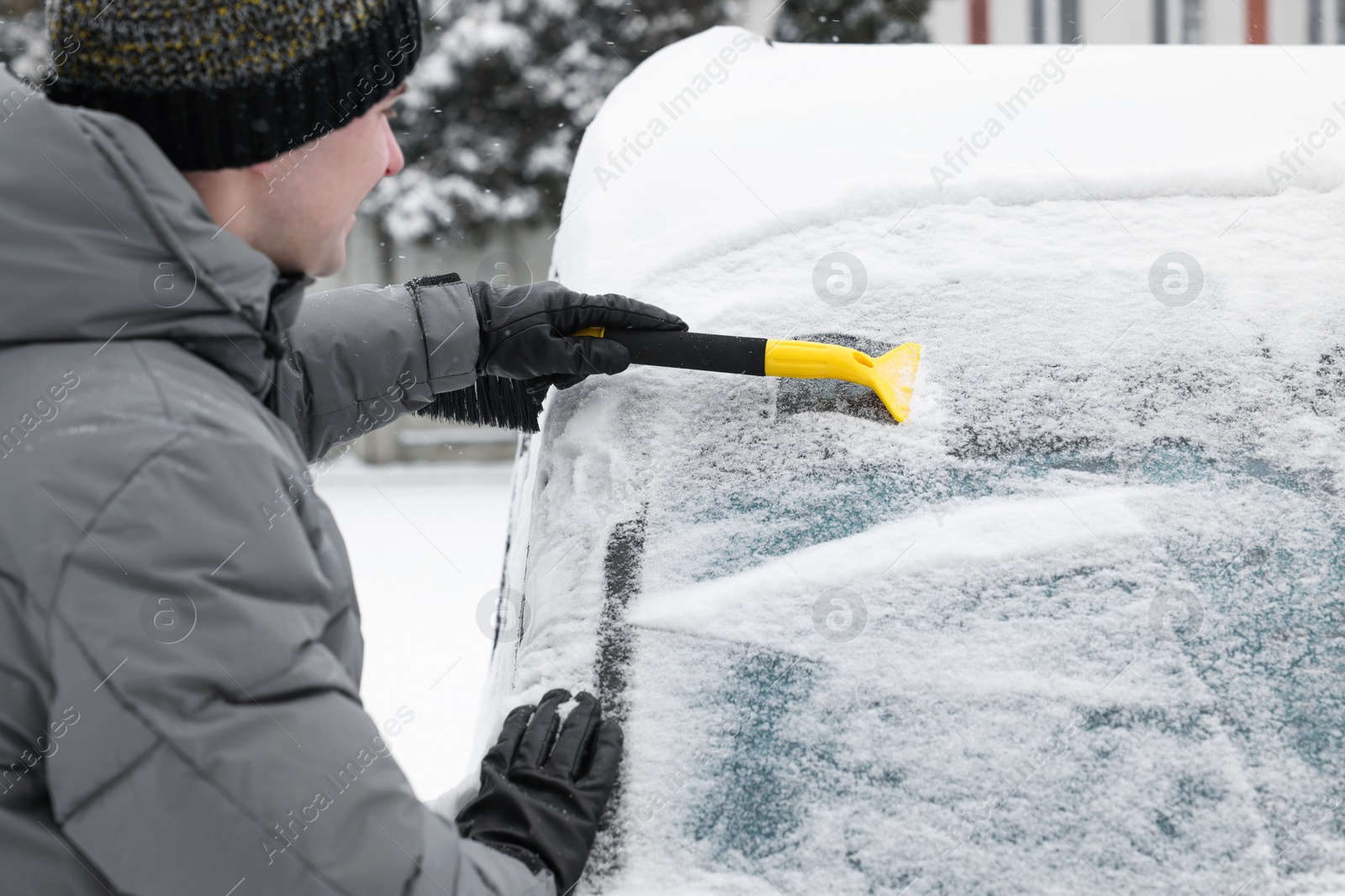 Photo of Man cleaning snow from car windshield outdoors