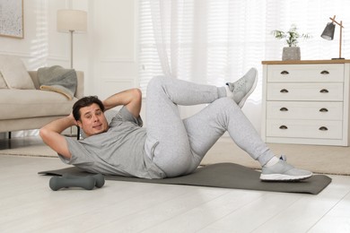 Photo of Overweight man doing abs exercise on mat at home