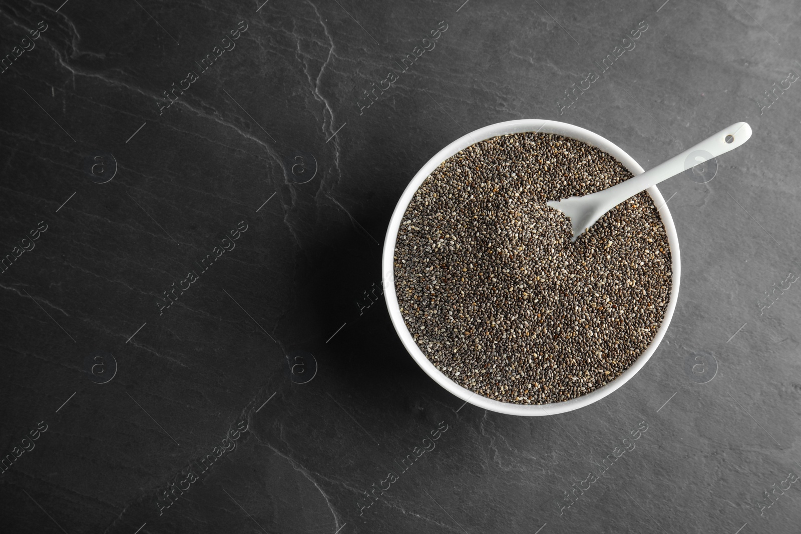 Photo of Bowl and spoon with chia seeds on grey background, top view. Space for text