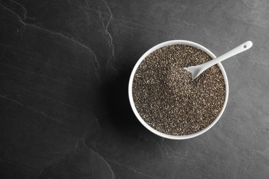 Photo of Bowl and spoon with chia seeds on grey background, top view. Space for text