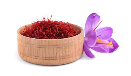 Dried saffron in wooden bowl and crocus flower on white background