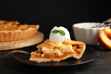 Photo of Slice of delicious peach pie with ice cream on black table