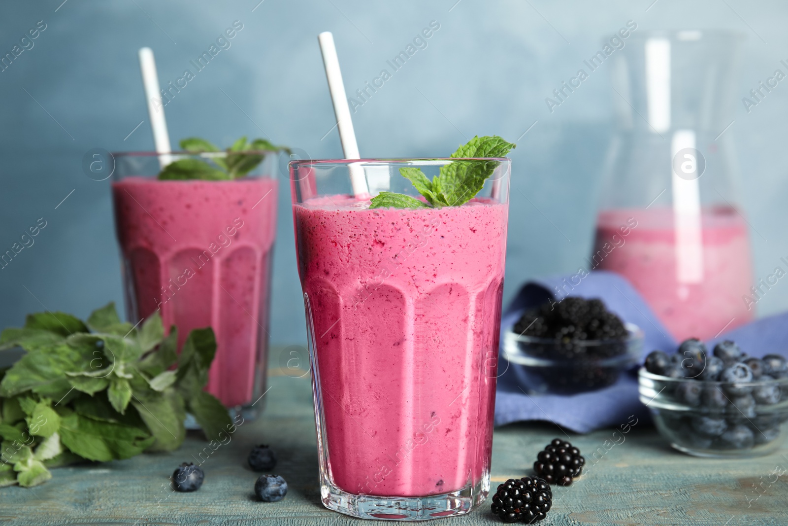 Photo of Tasty fresh milk shake with berries on light blue wooden table