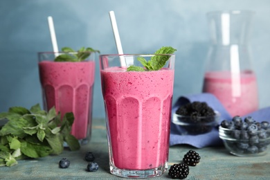 Tasty fresh milk shake with berries on light blue wooden table