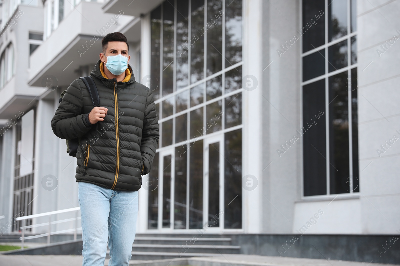 Photo of Man in medical face mask walking outdoors. Personal protection during COVID-19 pandemic