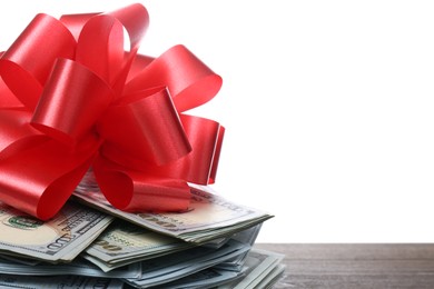 Photo of Pile of dollar bills with red bow on table against white background, closeup. Space for text