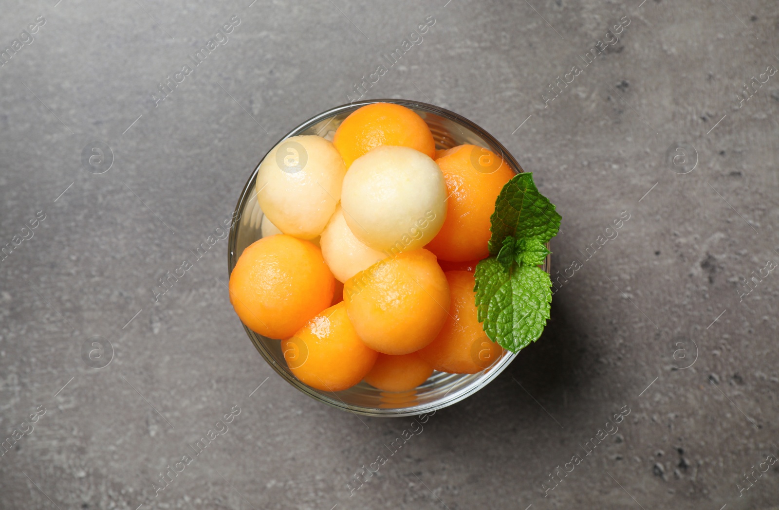 Photo of Melon balls and mint in glass on grey table, top view