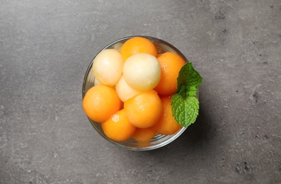 Melon balls and mint in glass on grey table, top view