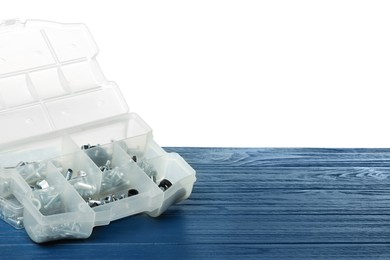 Plastic box with different bolts and nuts on grey wooden table against white background