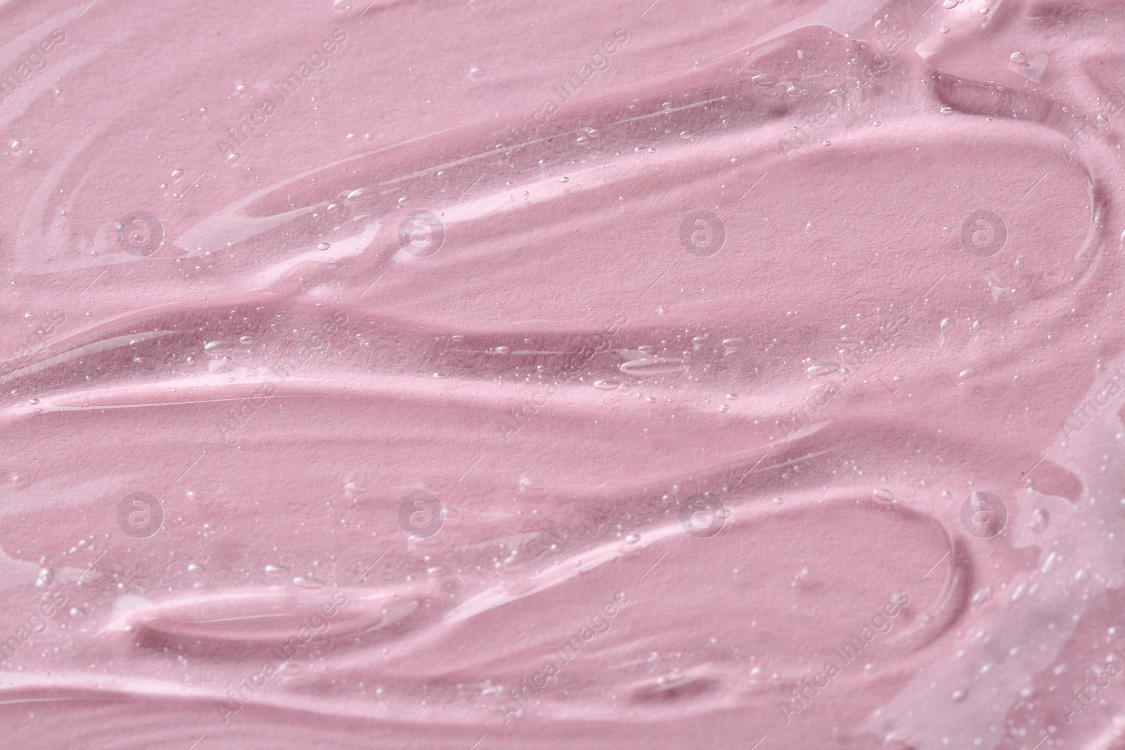 Photo of Clear cosmetic serum on pink background, macro view