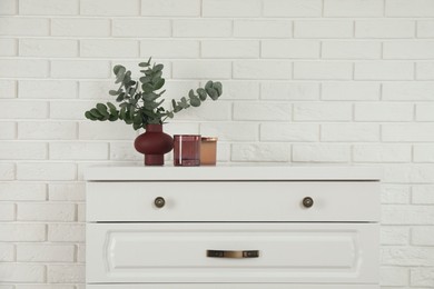 Modern chest of drawers with decor near white brick wall