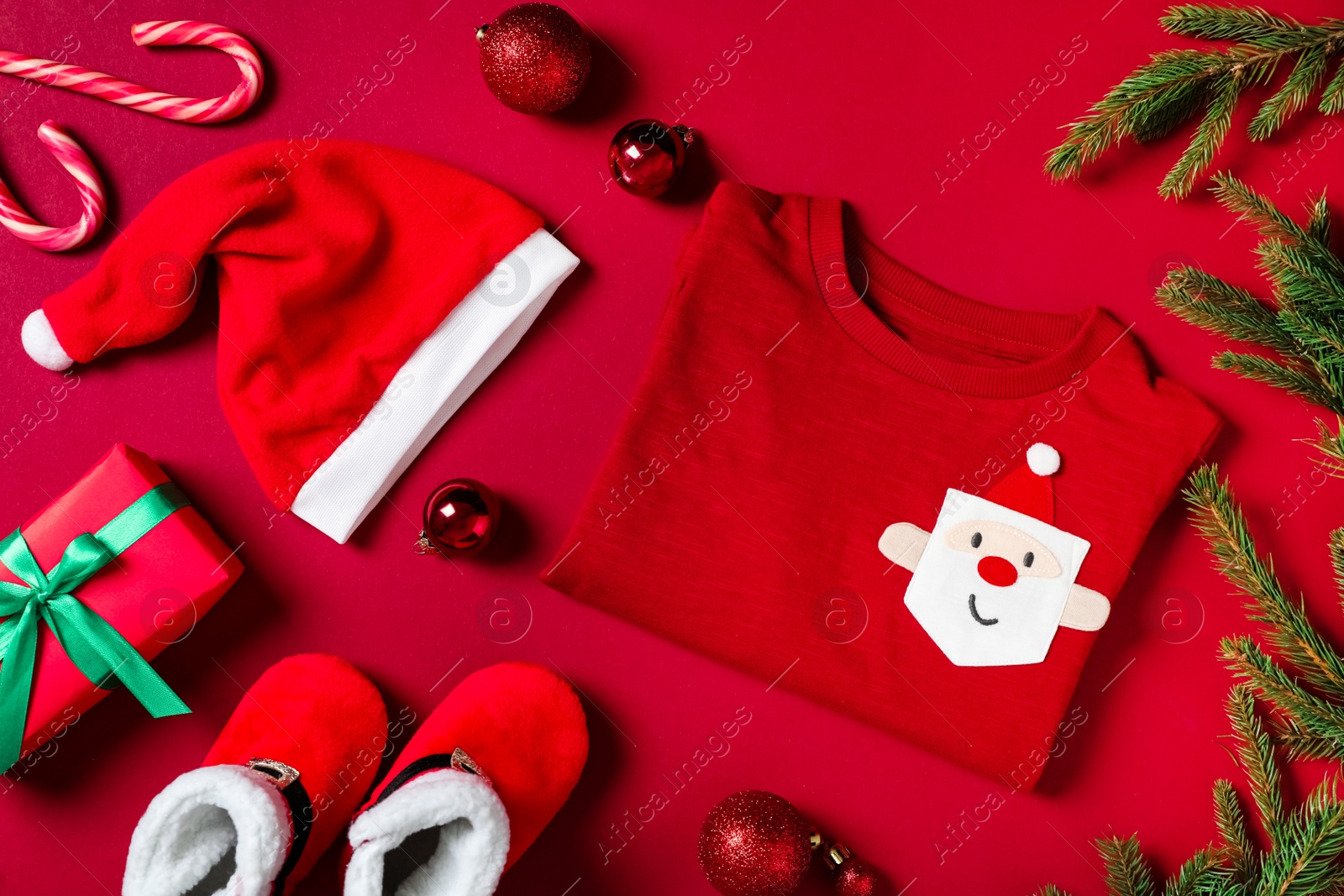 Photo of Flat lay composition with cute Christmas baby clothes on red background