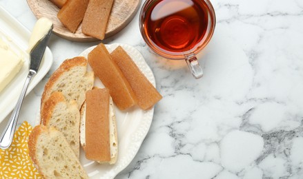 Delicious quince paste, bread, butter and cup of tea on white marble table, flat lay. Space for text